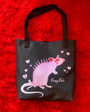 Black tote bag featuring a cute pink rat with a spiky back and long lashes with a pink bow on the tail. Surrounded by pink broken hearts 