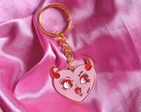 Gold plated pink heart with red horns with a face , sticking tongue out enamel keychain 