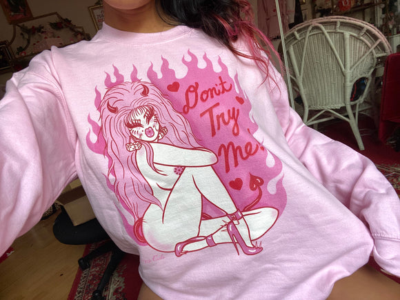 Pink cotton and polyester unisex crew neck sweat shirt featuring a sexy 80s lady with horns and big pink hair with the words “Don’t Try Me!” And pink flames in the background 