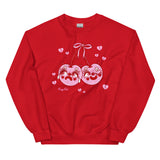 Red cotton and polyester unisex crew neck sweat shirt featuring kitschy pink devil cherries with clown makeup on. One cherry crying and the other winking. They are tied together with a pink bow and surrounded by pink broken hearts